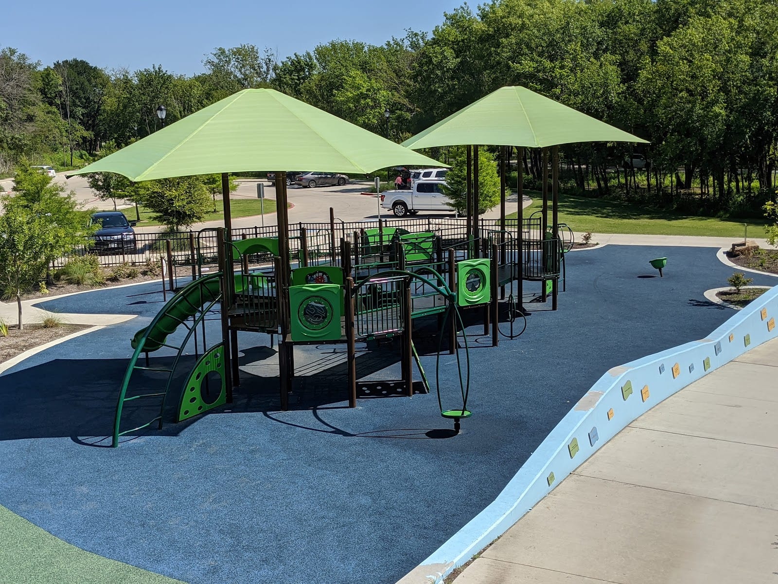 The playground at Bonnie Wenk Park, shaded by green canopies.
